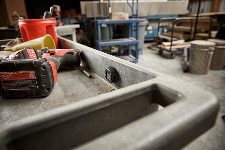 A Bluetooth tracking tag secured on jobsite cart beside drill driver