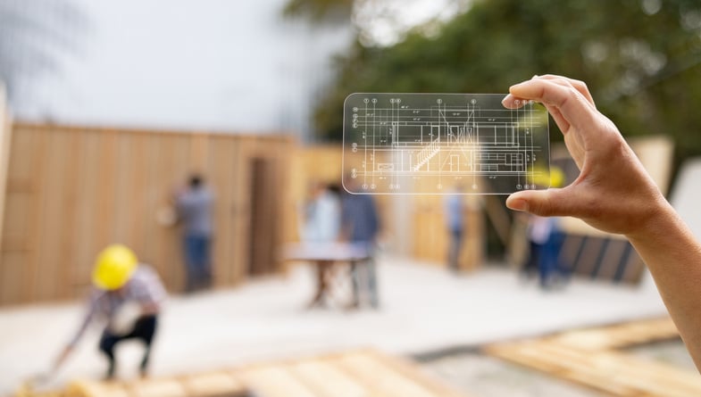 Architect at a construction site looking at a blueprint using an interactive smartphone app screen
