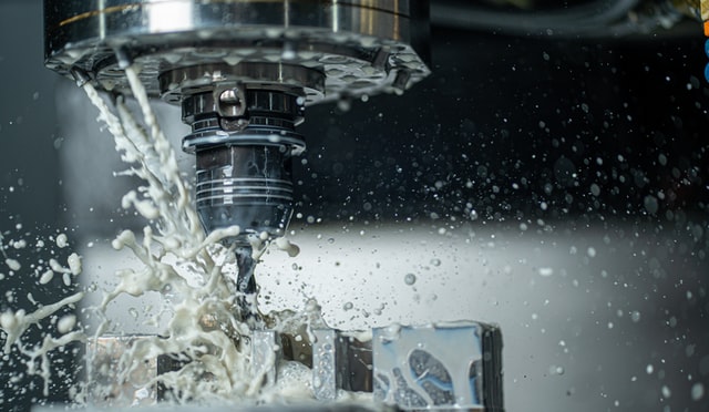 A CNC machine drills holes in steel using metal working lubricants