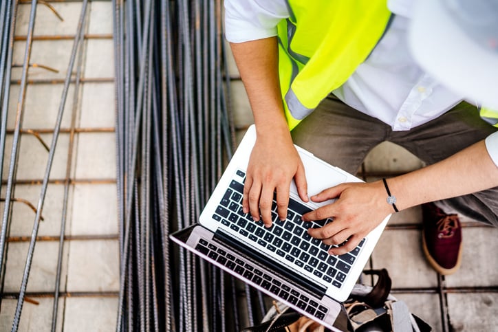 Construciton engineer on jobsite beside rebar types on computer-1