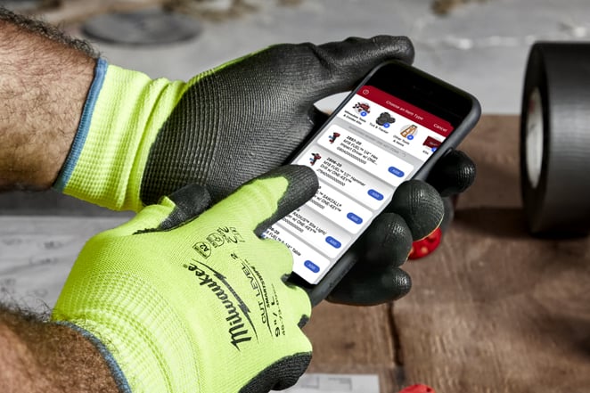 Contractor in yellow gloves operates smartphone with One-Key construction inventory app