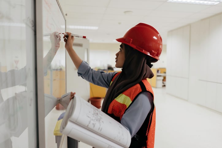 Female engineer developing business plan and writing on whiteboard