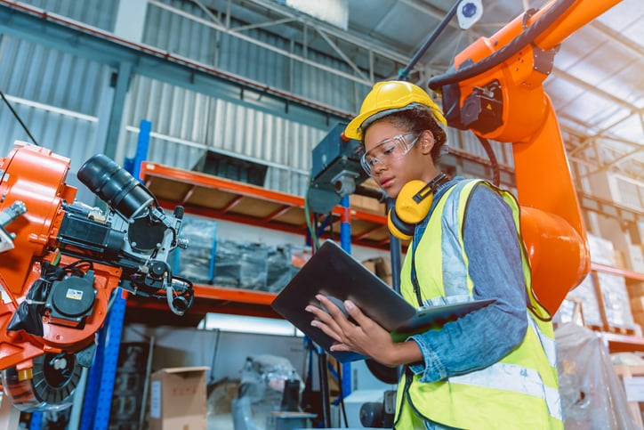 Female manufacturing engineer checks laptop in warehouse