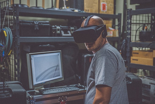 A worker wears AR goggles next to a computer in a tool crib