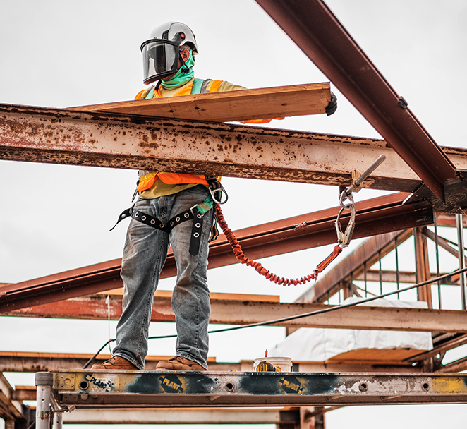 Image shows construction worker on jobsite completing work