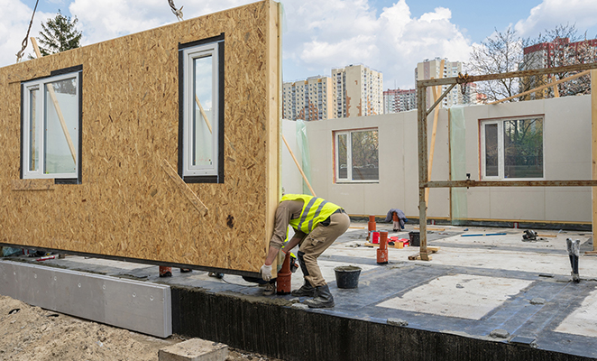 Construction worker installs prefabricated wall