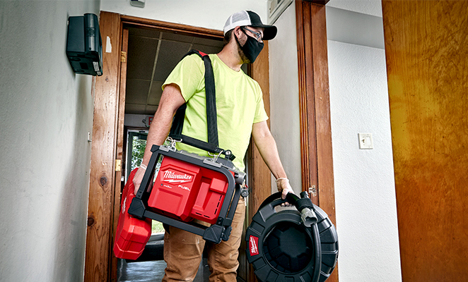 Plumber transports sectional plumbing equipment and drum machine into house