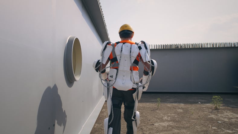 Male-builder-in exoskeleton-walking-on construction-site