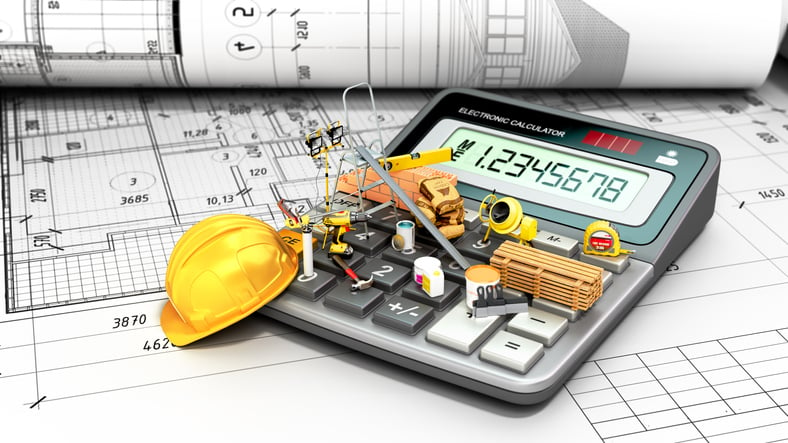 Stock photo of calculator beside hard hat and construction plans
