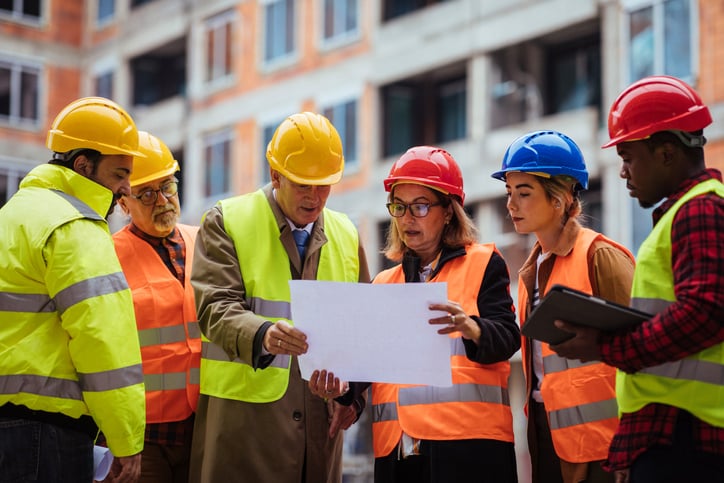 Team of construction professionals in hard hats check drawings