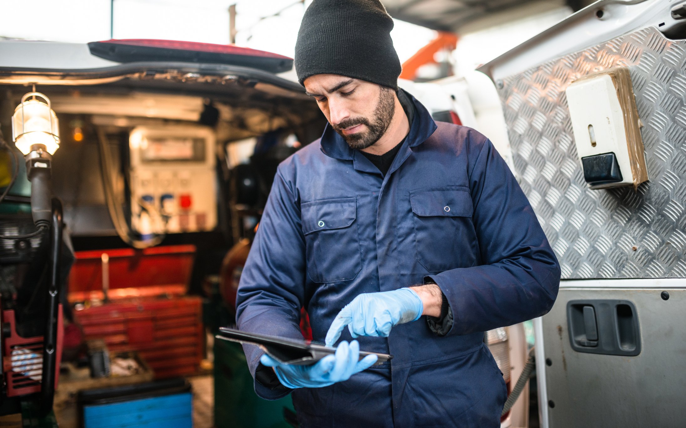 Tradesman-uses-tablet-device-beside-work-van