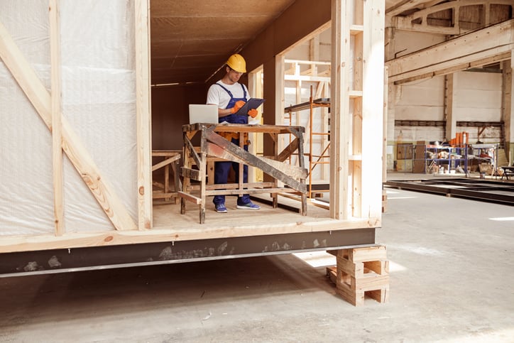 Tradesperson in prefab shop uses views iPad while working