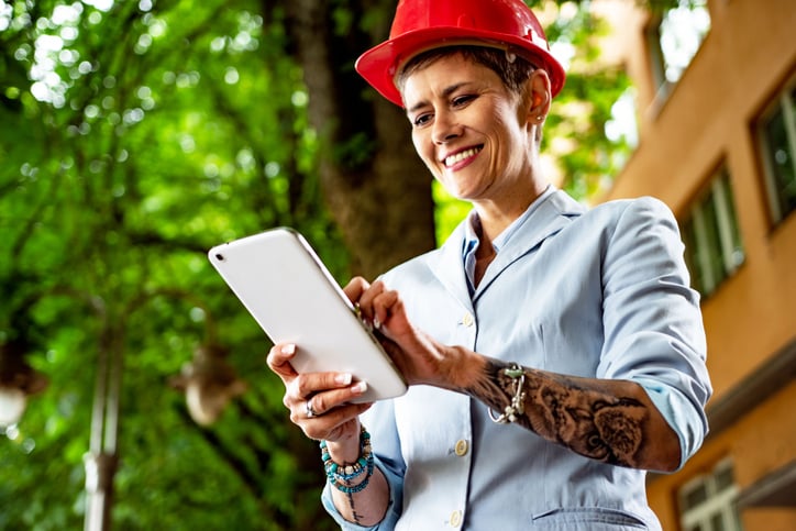 a female construction business owener with tattoos uses tablet device