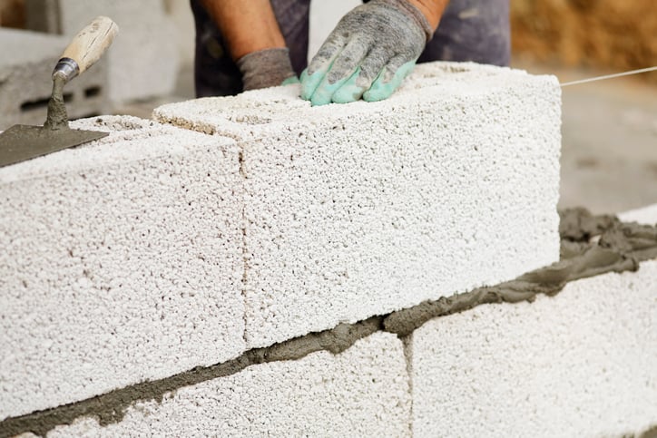 A brick mason installs cement block structured wall