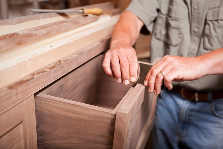 A cabinetmaker smooths wooden cabinet