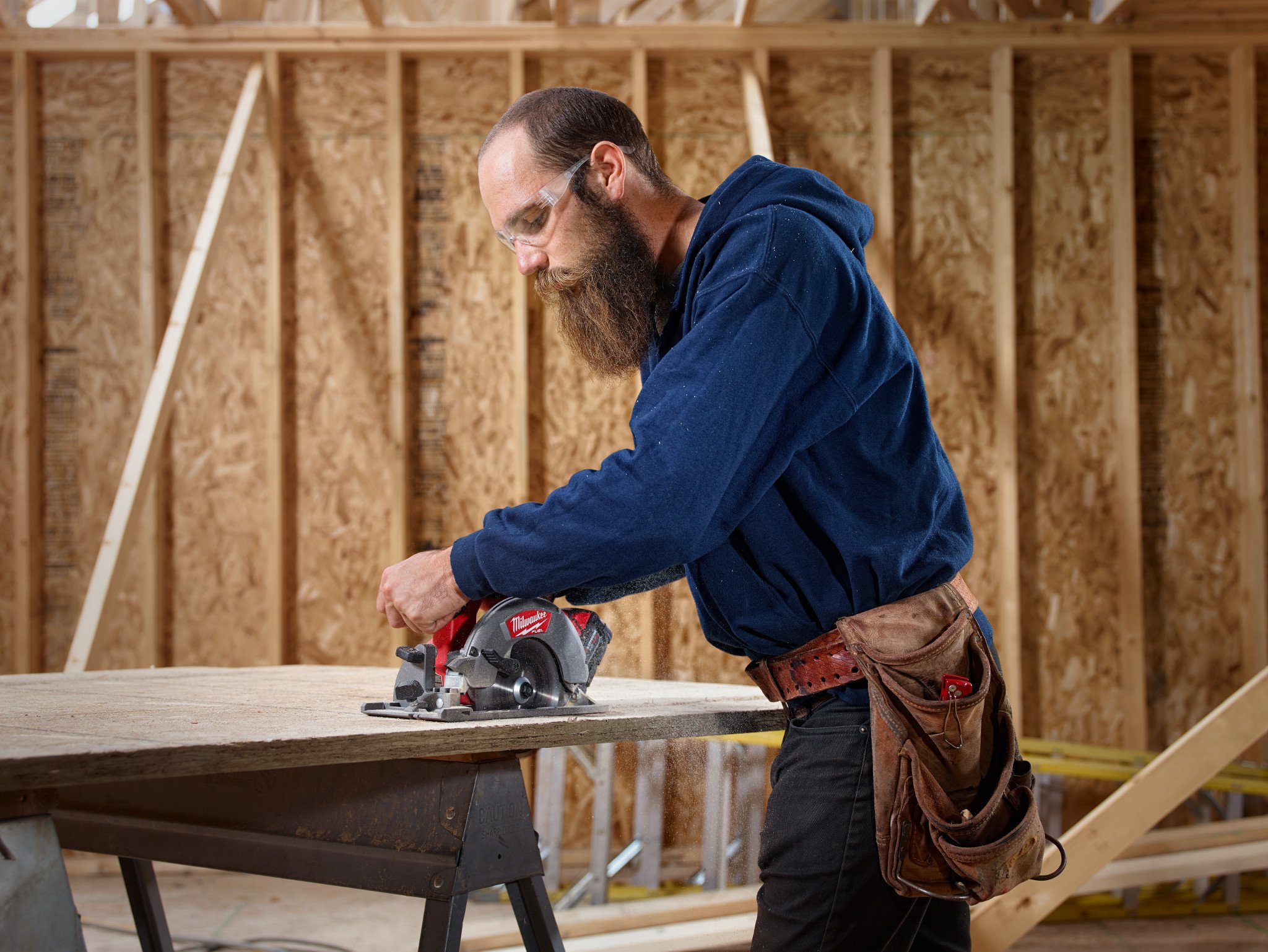 A general contractor uses a cordless Milwaukee circular saw to cut down plywood