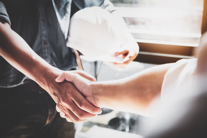 consruction worker with hard hat shakes business manager hand