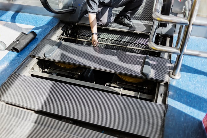 A technician services a non-operational escalator