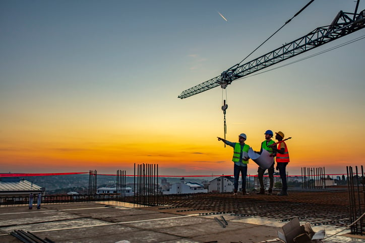 Three construction workers at sunset