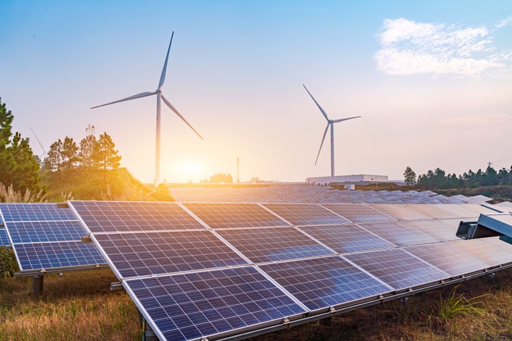 Daytime photograph of wind turbines in the background, solar panels in the foreground.