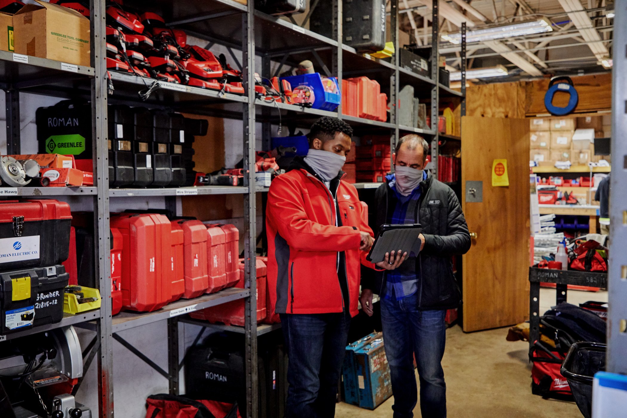 Two inventory managers consult over tablet device in tool crib