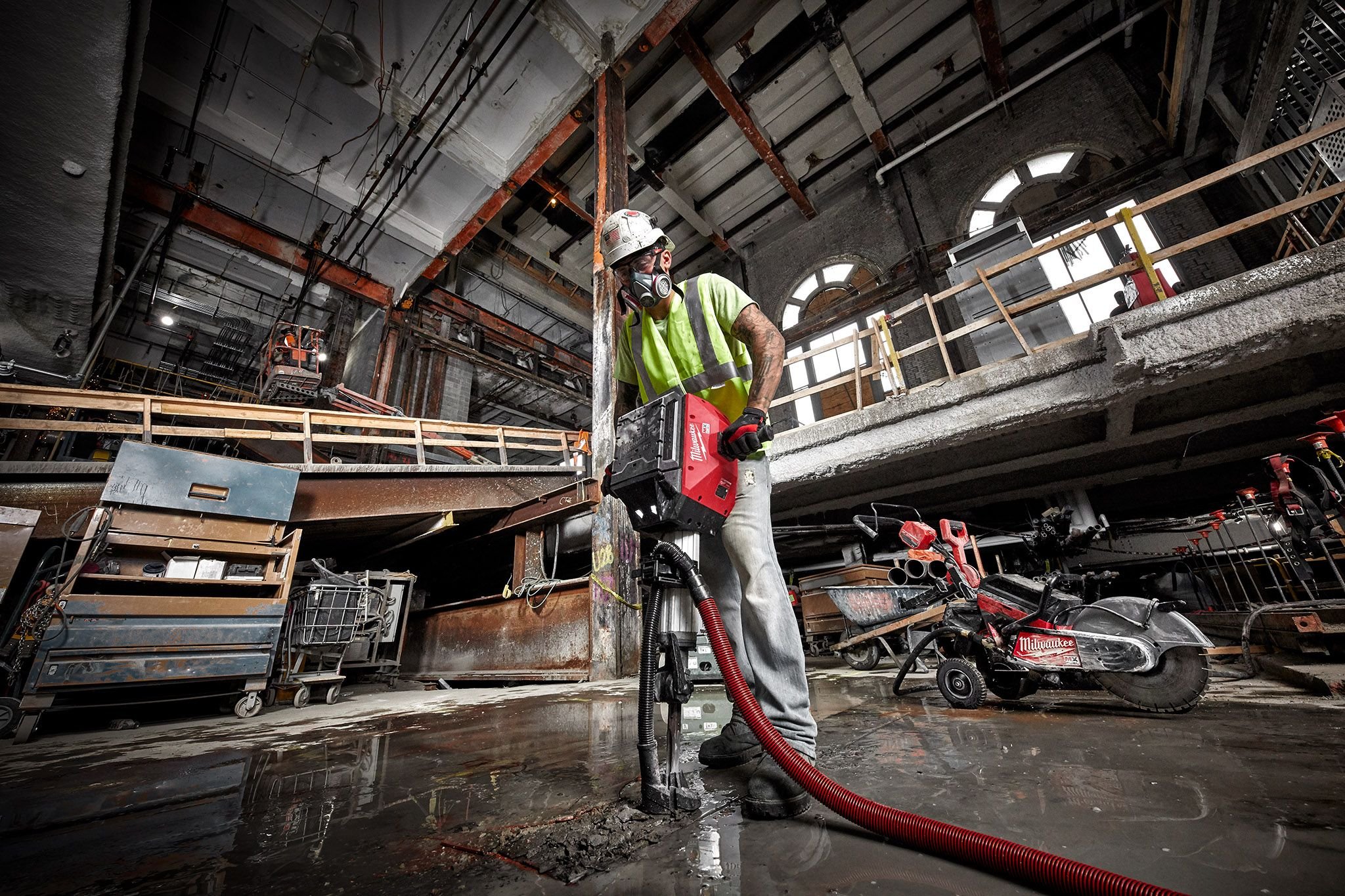 A cement mason uses a Milwaukee breaker to break up concrete floor