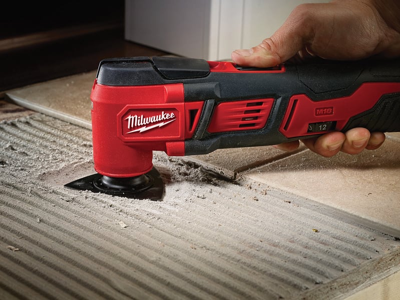 A general contractor uses an oscillating tool to install grout for tile floor