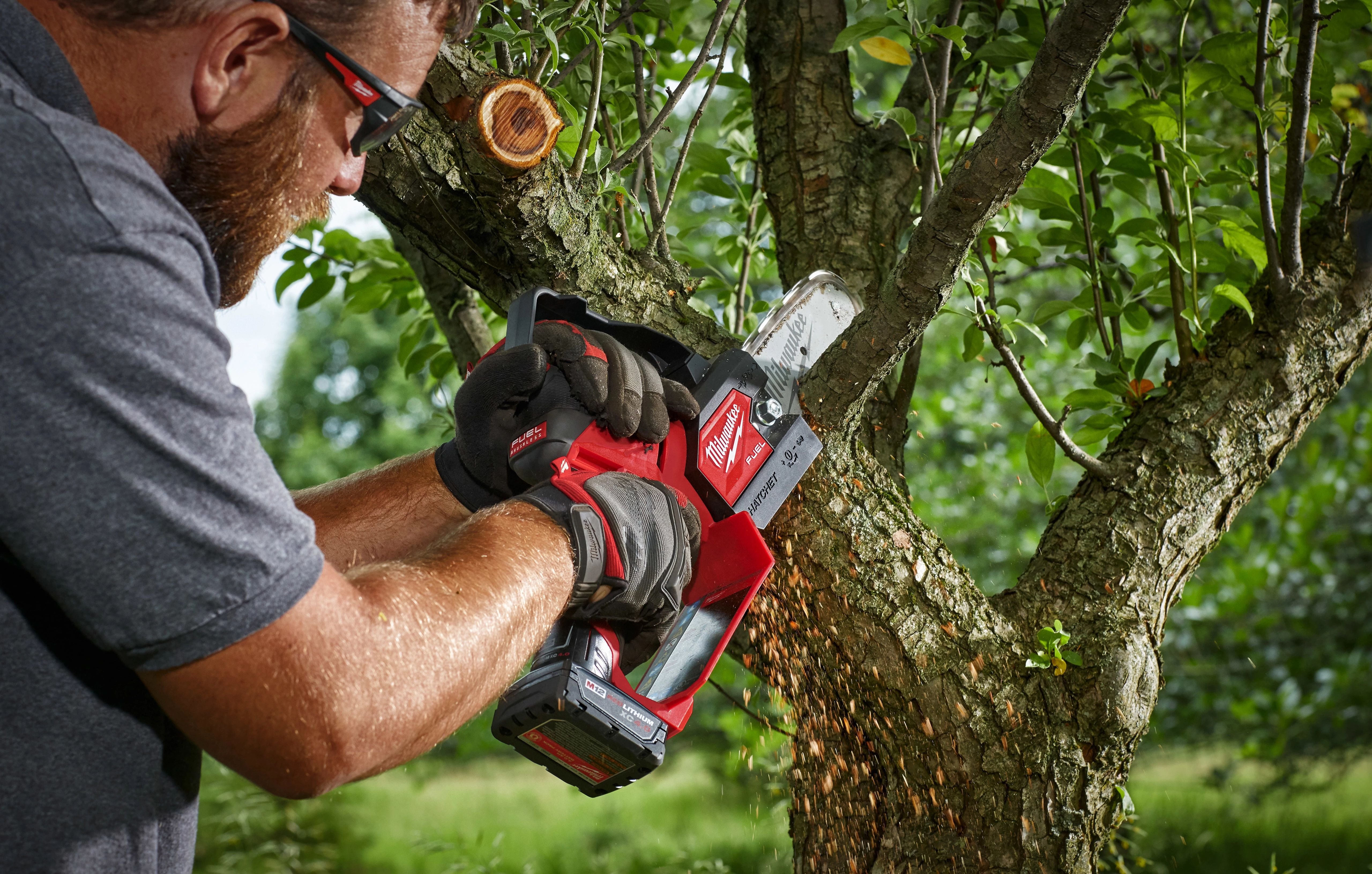 A landscape tree specialist utilizes a Milwaukee hatchet pruning saw to remove small branches in tight space 