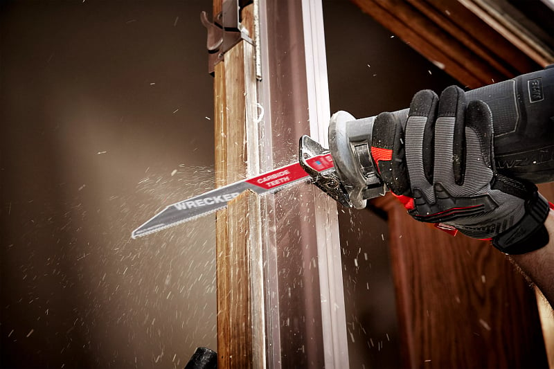 A general contractor uses a sawzall to cut through door panel