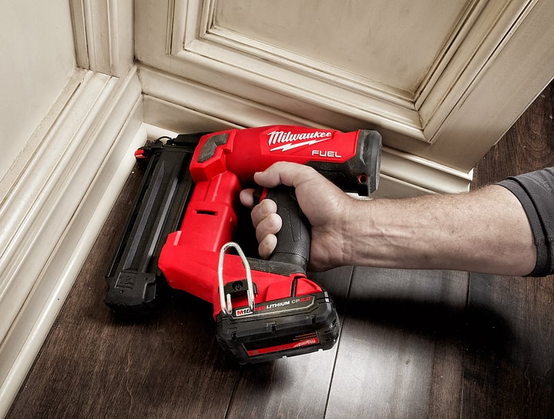 A general contractor uses a staple gun to install wall trim