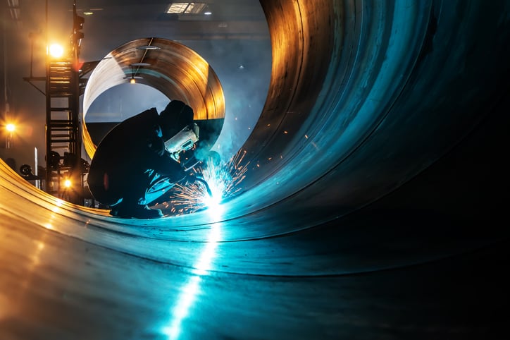 A welder fuses industrial steel plates