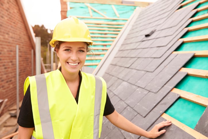 A young woman in a high-visibility vest and yellow hard hat learning the roofing trade