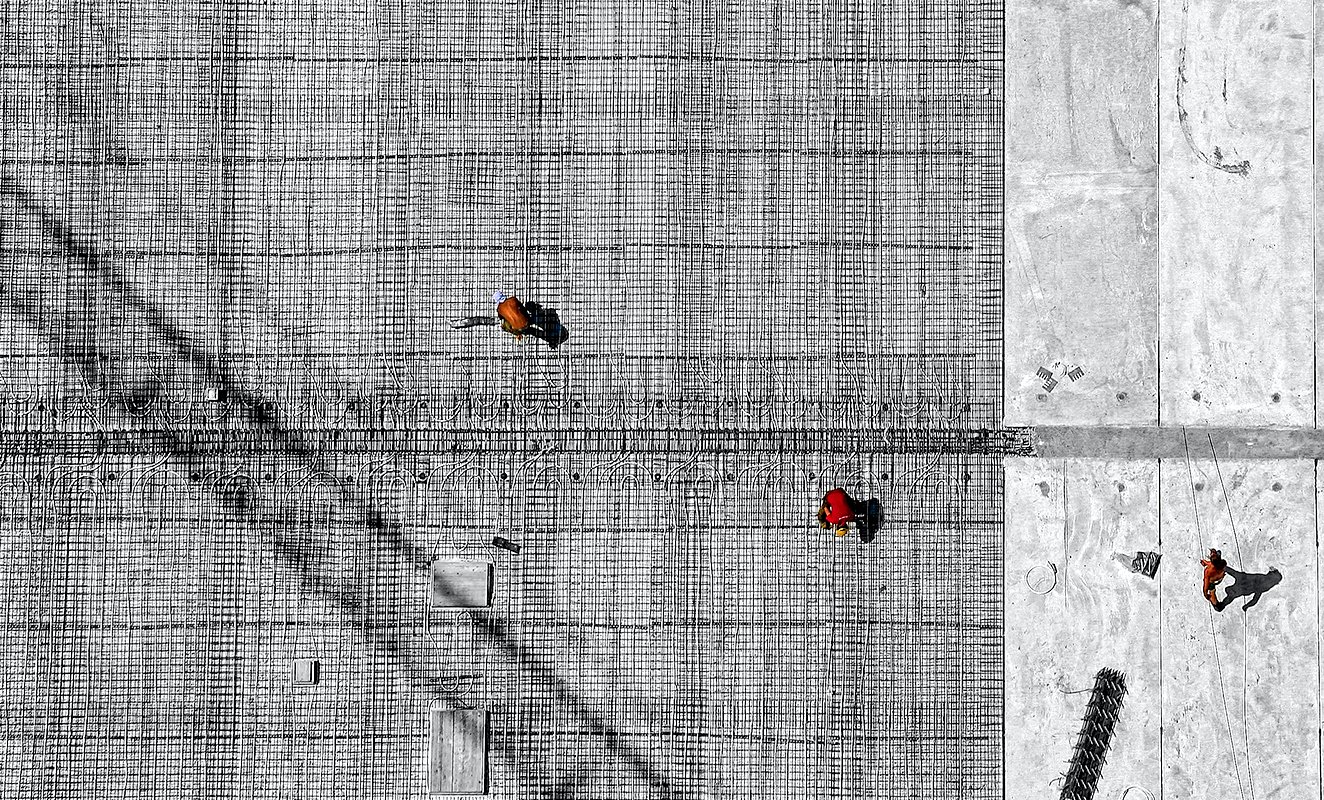An aerial shot of construction workers on jobsite distanced from each other