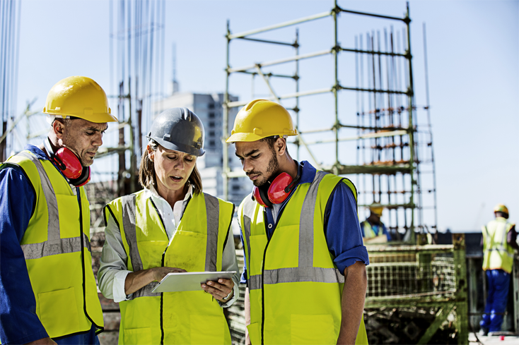 A team of construction technologists review project information on a digital tablet