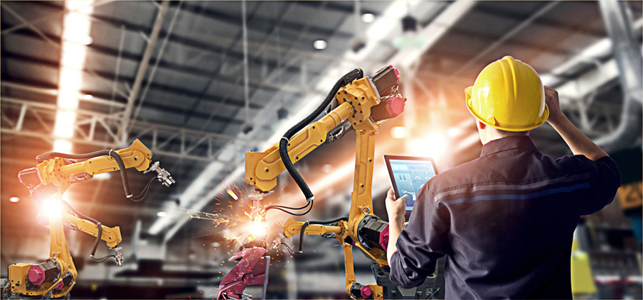 A construction technologist with a tablet on a jobsite oversees automated machinery