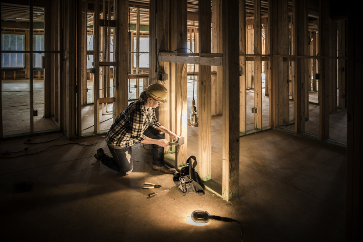 An electrician installs housing wiring on new construction